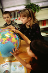 Three students looking at a globe