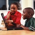 Elementary-aged boy and girl working on laptop in classroom