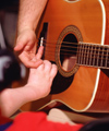 Child and teacher strumming a guitar