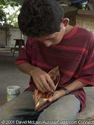 A young boy sands a wooden boat that will be sold to tourists.