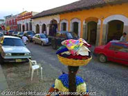 A Maya woman carries goods on her head down the streets of Antigua.