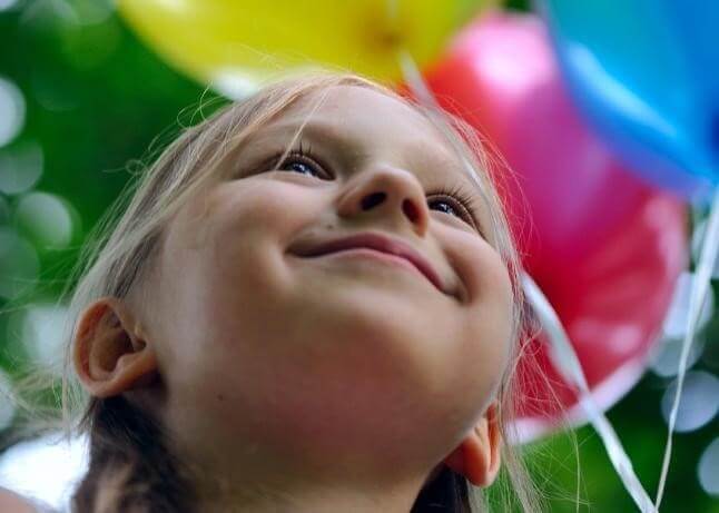Smiling Little Girl with Balloons in the Background