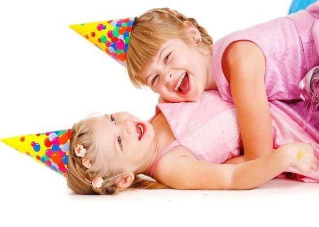 Two Laughing Little Girls Wearing Party Hats