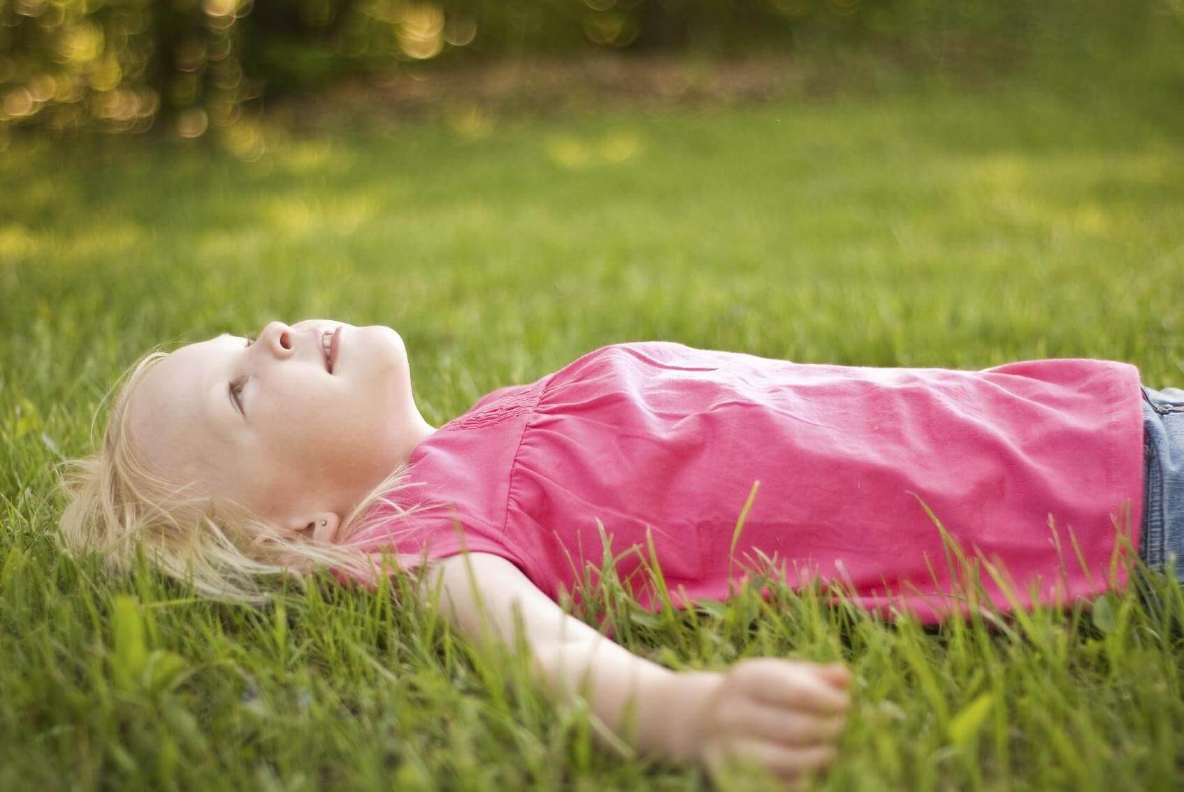 Little girls being. Девочка Сток. Girl lying on grass. Lie on the grass. Laying on the grass.