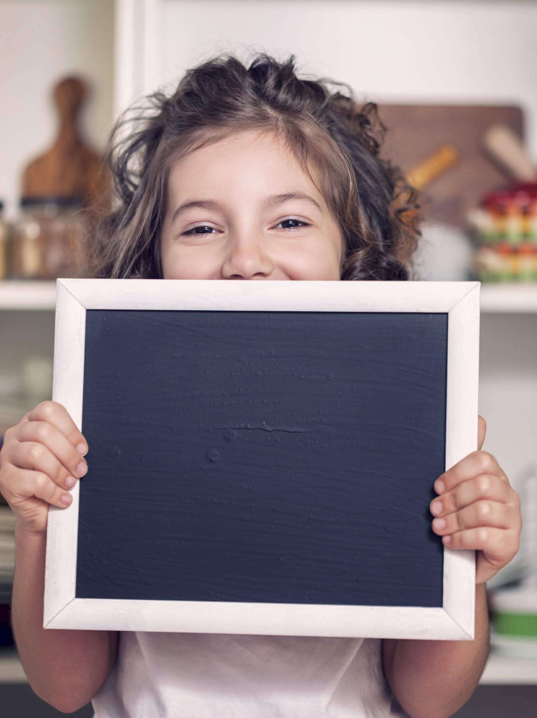 Little Girl Holding Up Blank Chalkboard
